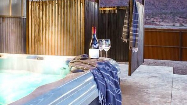 A spa area with a hot tub, a bottle of champagne, and a towel. - Slick Rock Retreat House (Moab)