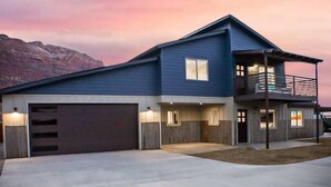 A modern two-story house with a garage, a balcony, and a mountain backdrop. - Slick Rock Retreat House (Moab)
