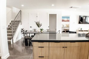 A modern kitchen with a central island, a dining area with chairs, and a staircase leading to another level. - Slick Rock Retreat House (Moab)