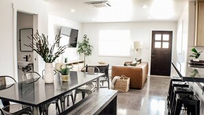 A modern kitchen with a dining area, featuring a long table, chairs, and a sofa. - Slick Rock Retreat House (Moab)