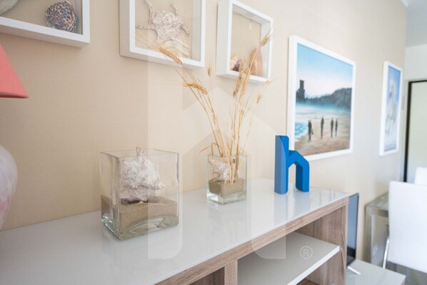 A modern room with a wooden desk, a glass vase with dried plants, and framed artwork on the wall.