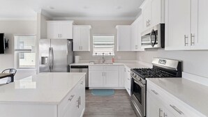 A modern kitchen with white cabinetry, stainless steel appliances, and a central island.