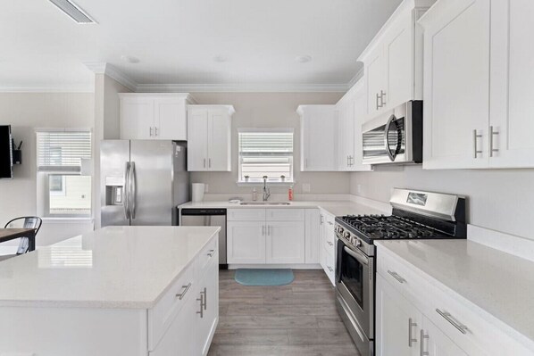 A modern kitchen with white cabinetry, stainless steel appliances, and a central island.