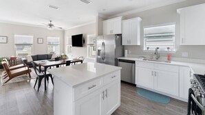 A modern kitchen with white cabinetry, a central island, and a dining area with a table and chairs.