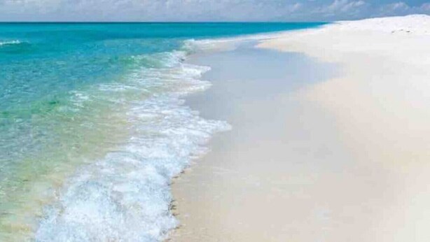 A beach with clear turquoise water and white sand.