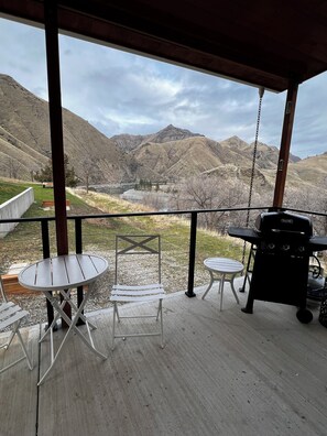 A covered outdoor area with a view of mountains, a barbecue grill, and outdoor seating.