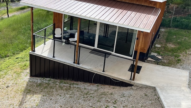 A modern house with a large glass window, a wooden deck, and a metal roof. - Hilltop riverview bunkhouse (Riggins)