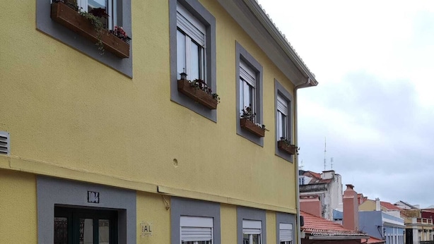 A yellow building with a green door, multiple windows, and a cobblestone street.