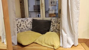 A cozy reading nook with a cushioned bench, patterned pillows, and a yellow throw blanket.