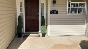 Une maison avec une porte d’entrée en bois foncé, une boîte aux lettres et une plaque indiquant le numéro de la maison.