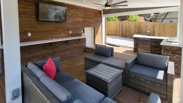 An outdoor patio with wicker furniture, a ceiling fan, and a TV mounted on the wall. - Outdoor Kitchen+Free Arcade+5 Miles to Downtown (Atlanta)