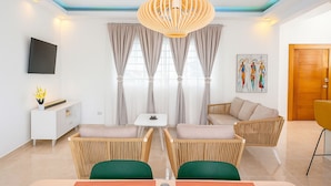 Un salon moderne avec un canapé, des fauteuils, un téléviseur et un tableau accroché au mur.