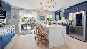 Una cucina moderna con mobili blu, un'isola centrale e un frigorifero in acciaio inossidabile.