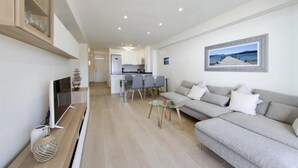 En moderne stue med sofa, fjernsyn og spiseplads med stole og bord.