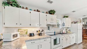 A modern kitchen with white cabinets, a granite countertop, a built-in oven, and a microwave.