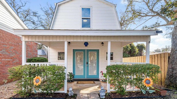 A two-story house with a front porch, a blue door, and a small window above the door.