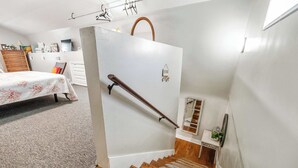 A staircase with a wooden handrail and carpeted steps leading to a landing.