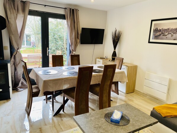 A dining area with a table set for four, a television mounted on the wall, and a framed picture above the table.