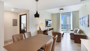Une chambre d’hôtel moderne dotée d’un coin repas, d’un canapé, d’une télévision et d’un balcon offrant une vue sur la ville.