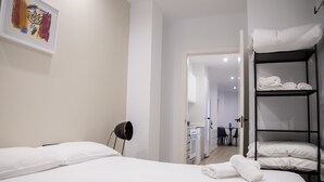 A hotel room with a bed, a black floor lamp, a painting on the wall, and a bunk bed with towels. - VLC HOST - Eixarchs 2 (València)