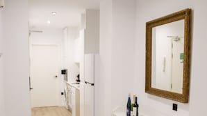 A modern kitchen with white cabinets, a white countertop, and a large mirror above the sink. - VLC HOST - Eixarchs 2 (València)