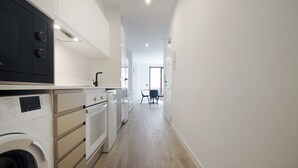 A modern kitchen with built-in appliances, a washing machine, and a dining area with a table and chairs. - VLC HOST - Eixarchs 2 (València)