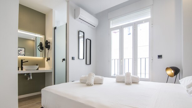 A modern hotel room with a large bed, a bedside table, a built-in sink, and a mirror. - VLC HOST - Eixarchs 4 (València)