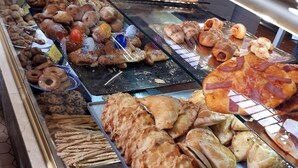 A bakery display case with various baked goods including pastries, croissants, and bread. - VLC HOST - Eixarchs 5 (València)