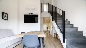 A modern living space with a dining area, a staircase, and a flat-screen TV mounted on the wall. - VLC HOST - Eixarchs 5 (València)