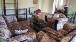 A living room with floral-patterned sofas, a wooden sideboard, and a vase with flowers. - Quiet, Spacious and Family Oriented (ANGUILLA)