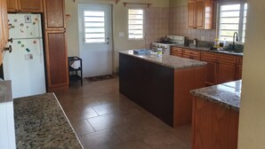A kitchen with wooden cabinets, a refrigerator, a stove, and a ceiling fan. - Quiet, Spacious and Family Oriented (ANGUILLA)