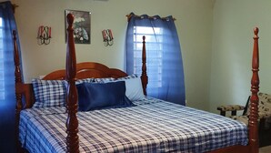 A bedroom with a four-poster bed, a ceiling fan, and a window with curtains. - Quiet, Spacious and Family Oriented (ANGUILLA)