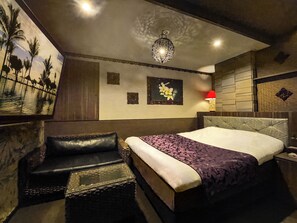 A hotel room with a bed, a chair, a wall-mounted lamp, and a painting of palm trees. - HOTEL Balibali ANNEX (Tokyo)