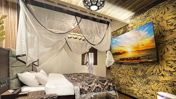 A bedroom with a bed, a TV, a coffee table, and a wall with a floral pattern. - HOTEL Balibali ANNEX (Tokyo)