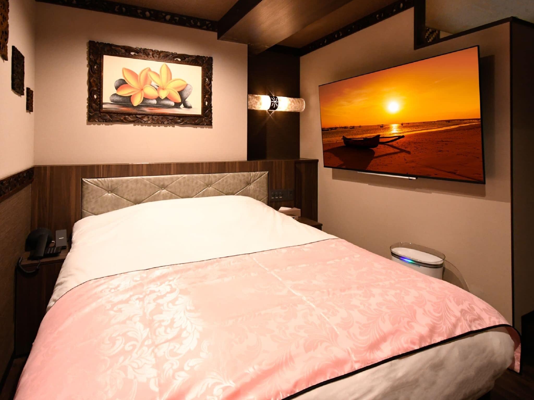 Una habitación de hotel con una cama, un cuadro, un televisor y una mesita de noche.