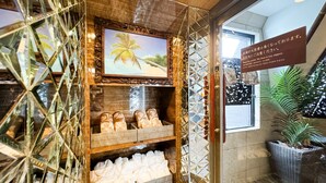 A hotel reception area with a wooden display case containing slippers and a framed picture of a palm tree. - HOTEL Balibali ANNEX (Tokyo)