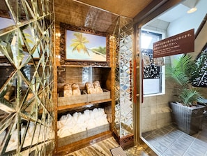 A hotel reception area with a wooden display case containing slippers and a framed picture of a palm tree.