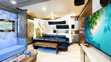 A modern bedroom with a large bed, a sofa, a TV, and a decorative wall.