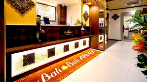 A reception desk with a 'Bali Bali Annex' sign, a computer, and decorative wall art. - HOTEL Balibali ANNEX (Tokyo)