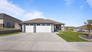 Een modern huis met een garage, een verzorgd gazon en een heldere lucht.