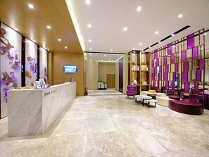 A hotel lobby with a reception desk, seating area, and decorative panels.