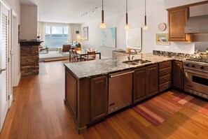 A modern kitchen with wooden cabinets, a granite countertop, and stainless steel appliances. - Top-Floor Views, Pool & Hot Tub (Sandpoint)