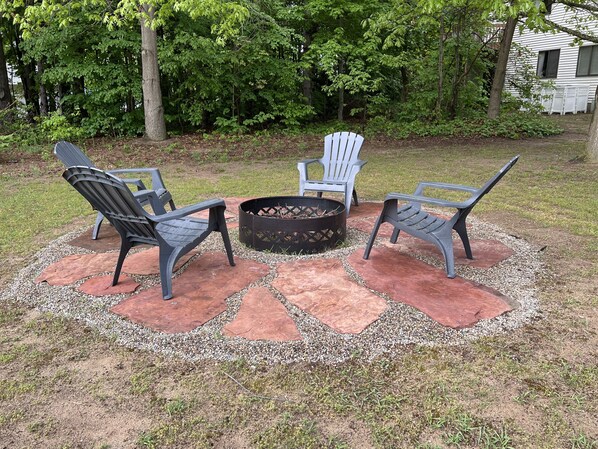 Un patio con sillas Adirondack y un hogar para fuego.