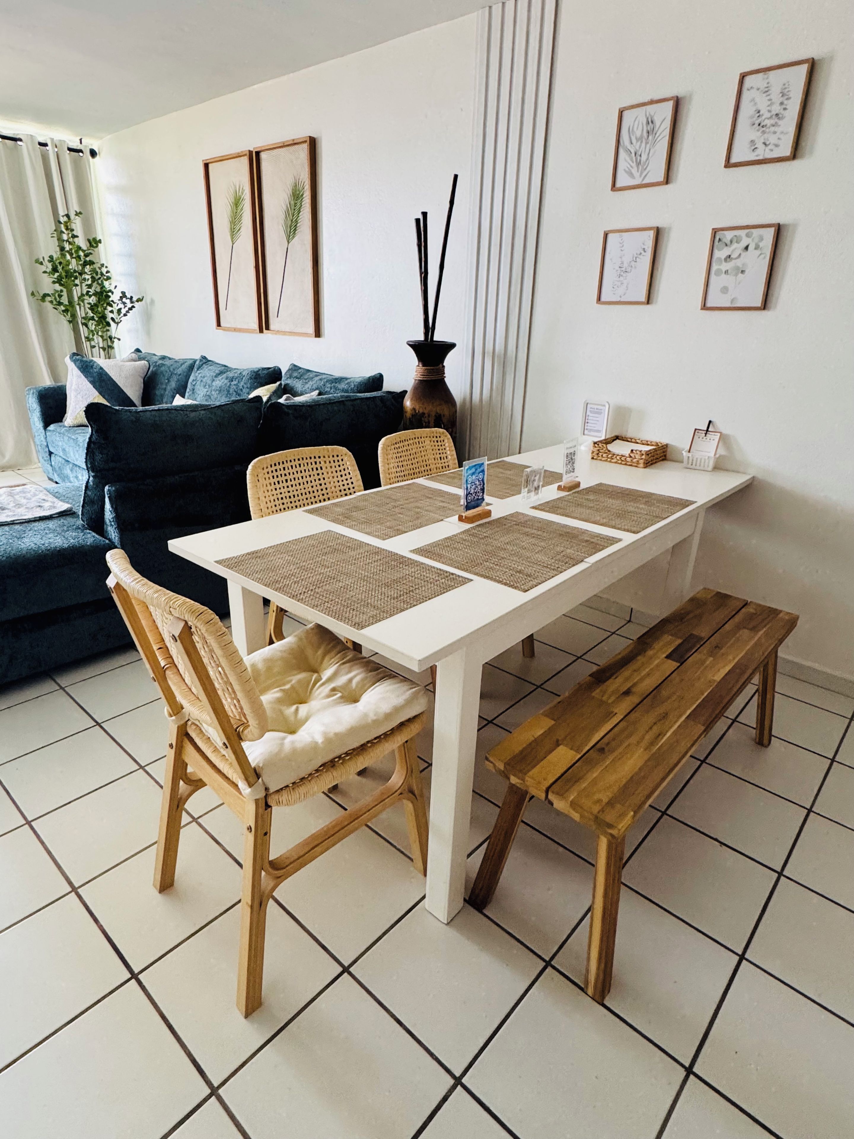 A dining area with a white table, woven placemats, and wooden chairs.