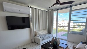A living room with a sofa, a coffee table, a TV mounted on the wall, and a ceiling fan. - Spacious 3 bedroom apartment with sea view short drive to ferry station. (Ceiba)