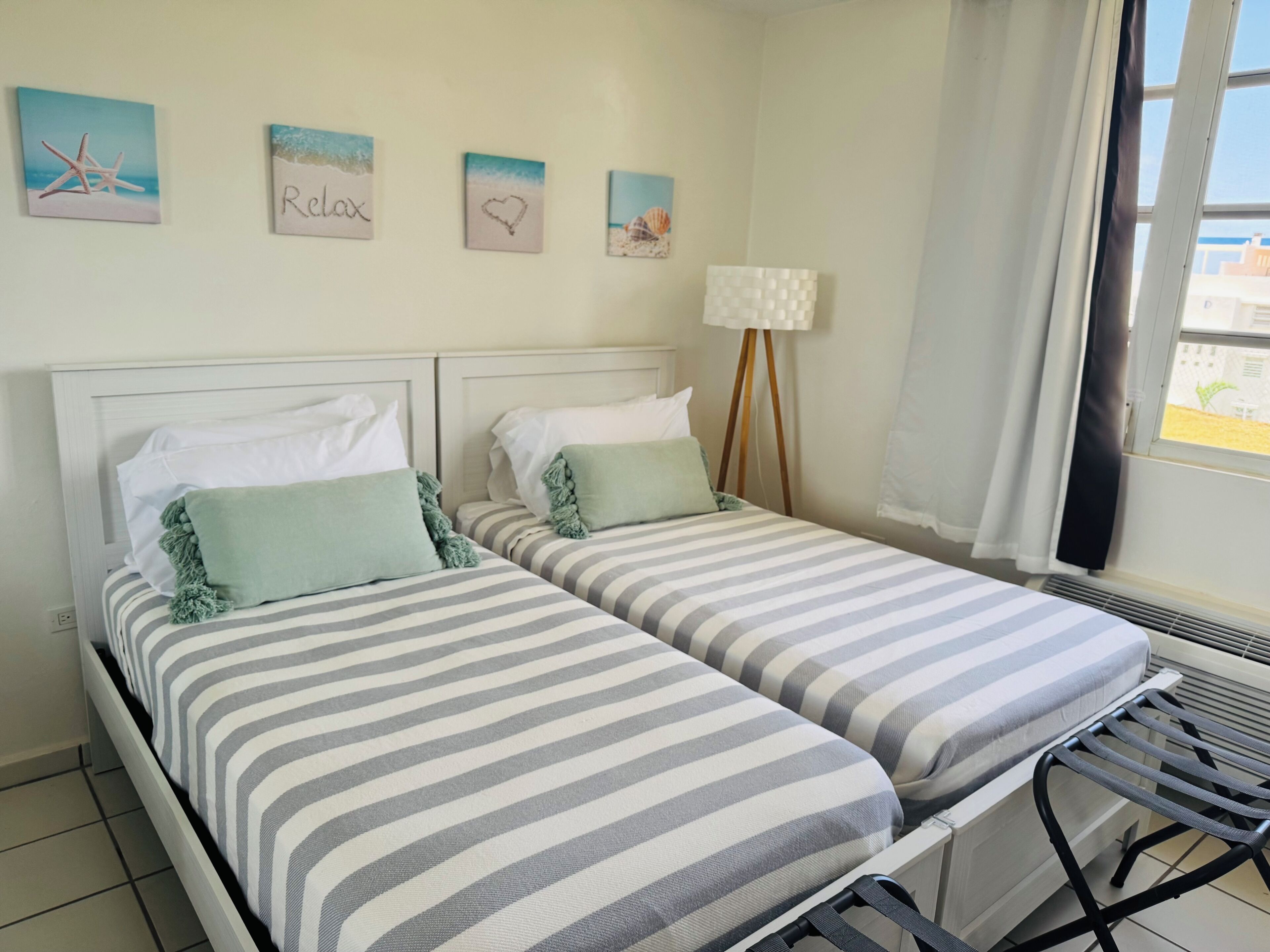Een kamer met twee bedden, een staande lamp en wanddecoratie.