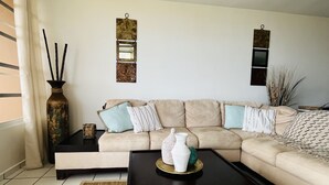 A living room with a sectional sofa, a coffee table, a ceiling fan, and decorative wall art. - Spacious 3 bedroom apartment with sea view short drive to ferry station. (Ceiba)