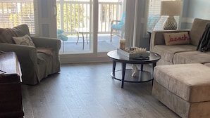 Ein Wohnzimmer mit einer Couch, einem Couchtisch und einem Sessel. Eine Schiebetür führt zu einem Balkon.