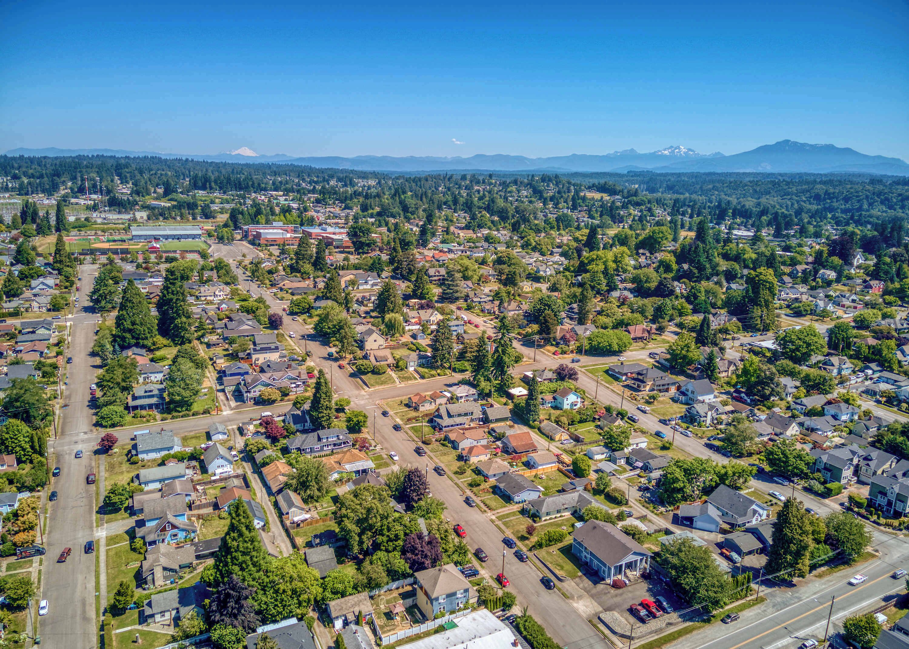 An aerial view of a residential area with houses, roads, and a large building in the distance.