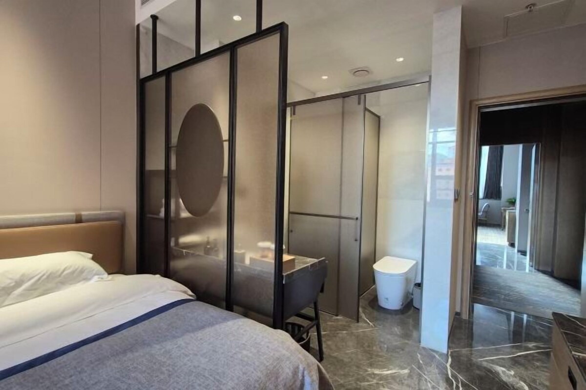 Une chambre d’hôtel équipée d’un lit, d’un bureau, d’un miroir et offrant une vue sur la salle de bain et le couloir.